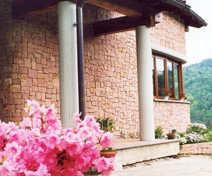 EDILIZIA RESIDENZIALE-Nuova villetta singola a Valdilana, Trivero (BI) - 1995
Questo edificio, collocato in posizione dominante in cima a una collina, ha una disposizione in pianta con una forma leggermente arcuata, in modo da privilegiare la facciata sud, dove la vista e l'esposizione sono migliori. Abbiamo realizzato la struttura in cemento armato seguendo le particolari forme della pianta dell'edificio, mentre abbiamo eseguito il rivestimento esterno con  blocchetti squadrati a mano di porfido rosso proveniente dalle cave di Cuasso al Monte (VA). A nostro avviso tutto questo ha reso l’effetto finale molto particolare. Infine, nel piano giorno è presente il giardino interno che si affaccia per mezzo di vetrate sui locali interni e prende la luce naturale dall'alto. 